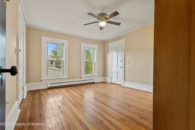 an empty room with wooden floor and windows