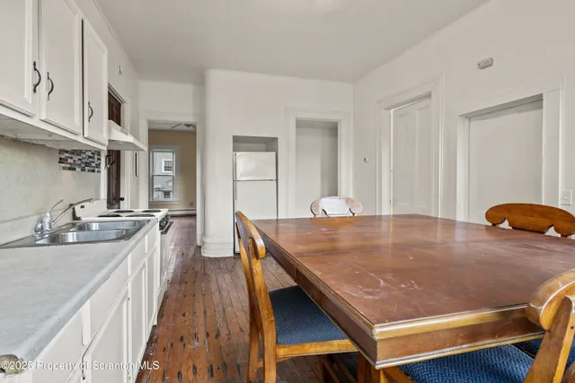a room with stainless steel appliances granite countertop a sink a table and chairs