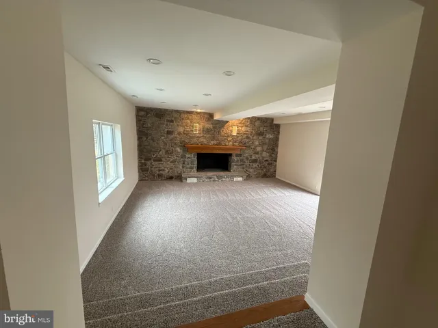 a view of an empty room with a fireplace and a window