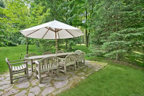 a view of a patio with table and chairs potted plants and floor to ceiling window