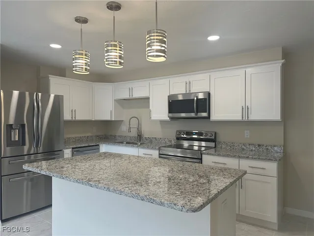a kitchen with stainless steel appliances granite countertop a sink a stove and a refrigerator