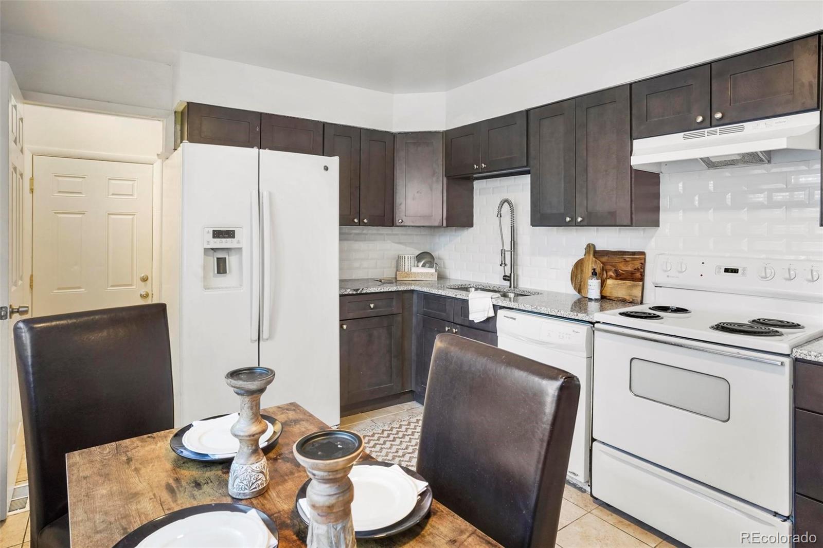 5522 Carson Street Denver, CO 80239 - Photo 14 of 40 a kitchen with stainless steel appliances granite countertop a refrigerator a sink a stove a dining table and chairs
