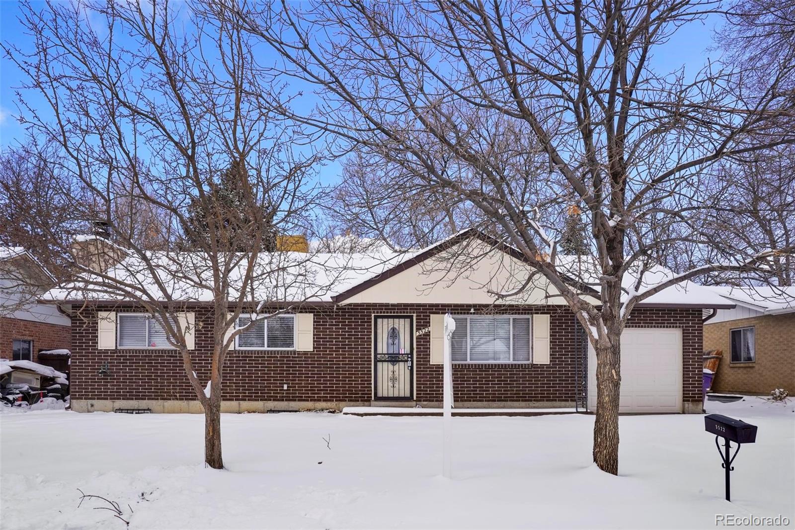 5522 Carson Street Denver, CO 80239 - Photo 2 of 40 a front view of a house with a yard covered in snow