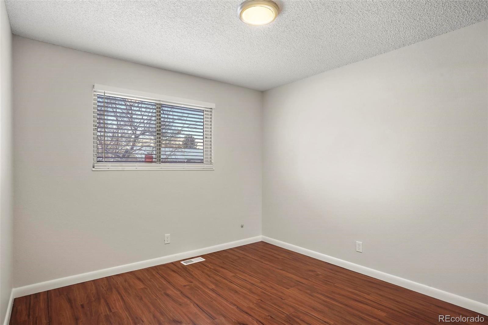 5522 Carson Street Denver, CO 80239 - Photo 23 of 40 a view of an empty room with wooden floor and a window