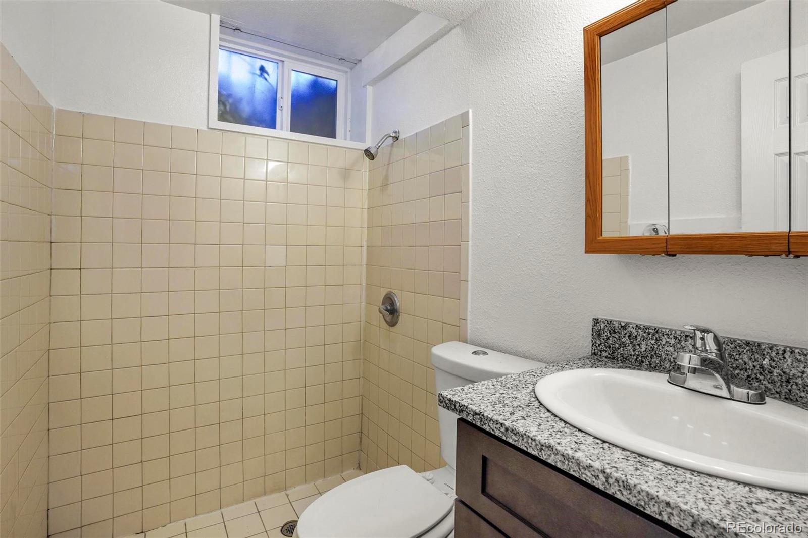 5522 Carson Street Denver, CO 80239 - Photo 29 of 40 a bathroom with a granite countertop toilet sink and mirror