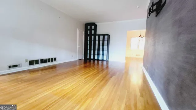 a view of an empty room with wooden floor and a bathroom
