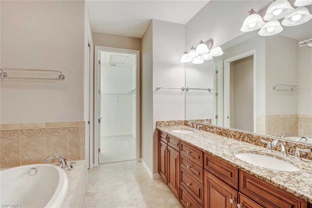 8975 Malibu Street, Unit 1302 Naples, FL 34113 - Photo 15 of 34 a spacious bathroom with a granite countertop sink a mirror and a bathtub