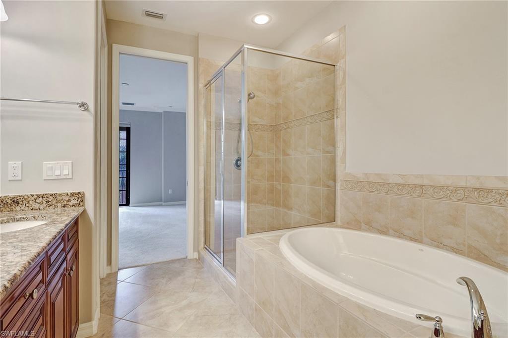 8975 Malibu Street, Unit 1302 Naples, FL 34113 - Photo 16 of 34 a bathroom with a granite countertop bathtub shower sink and vanity