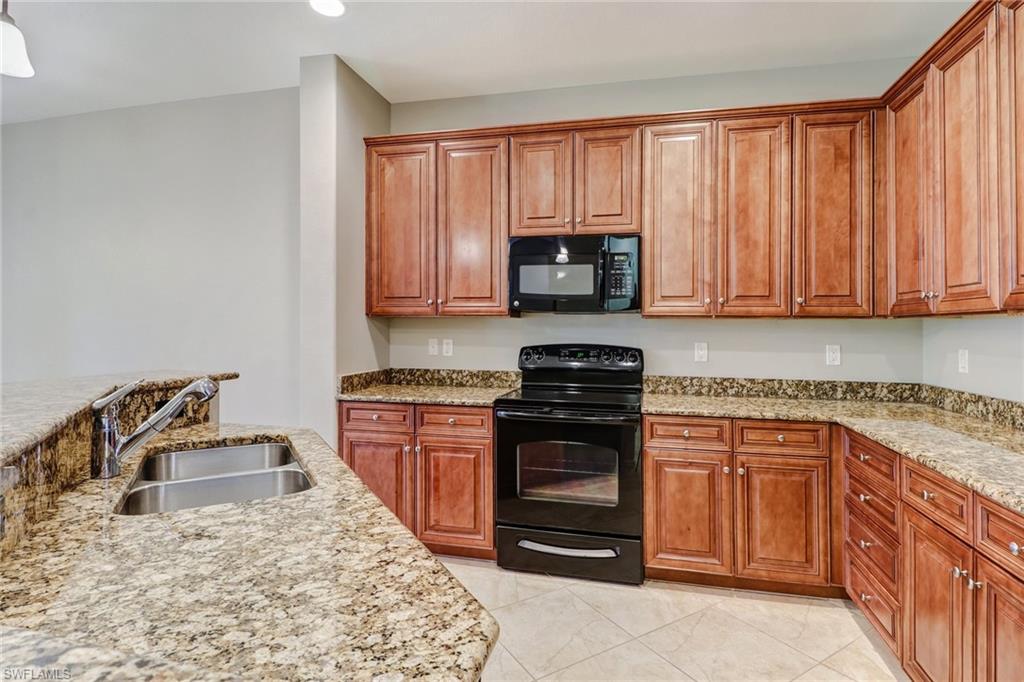 8975 Malibu Street, Unit 1302 Naples, FL 34113 - Photo 10 of 34 a kitchen with stainless steel appliances granite countertop a stove a sink and a microwave