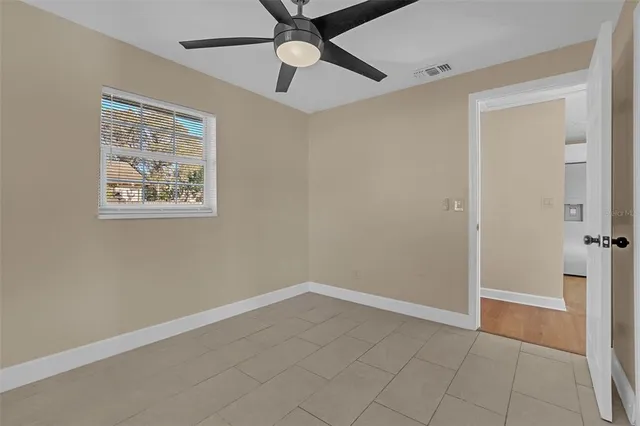 an empty room with windows and fan