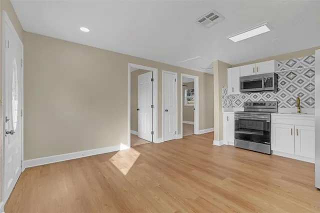 a view of a livingroom with a fireplace a ceiling fan and windows