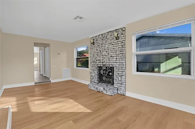 a view of an empty room with a fireplace and a window