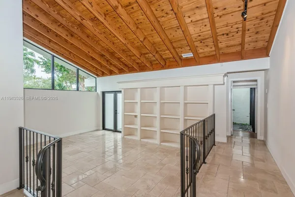 a large white kitchen with a window and refrigerator