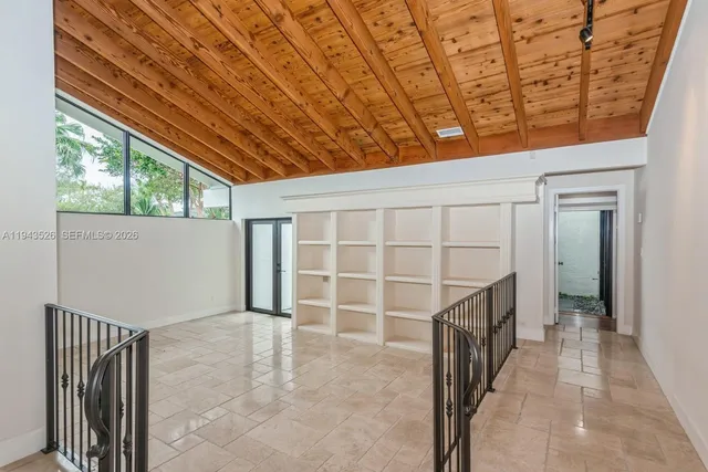 a large white kitchen with a window and refrigerator