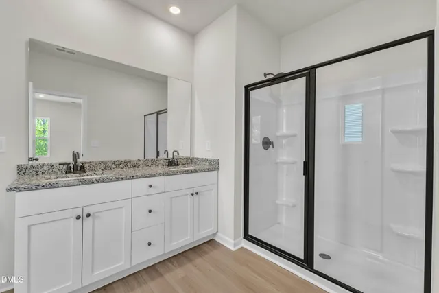 a bathroom with a granite countertop sink a mirror and a shower