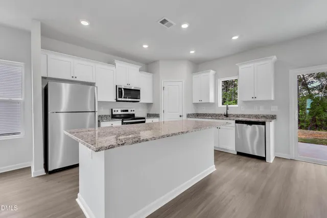 a kitchen with stainless steel appliances granite countertop a refrigerator sink and white cabinets