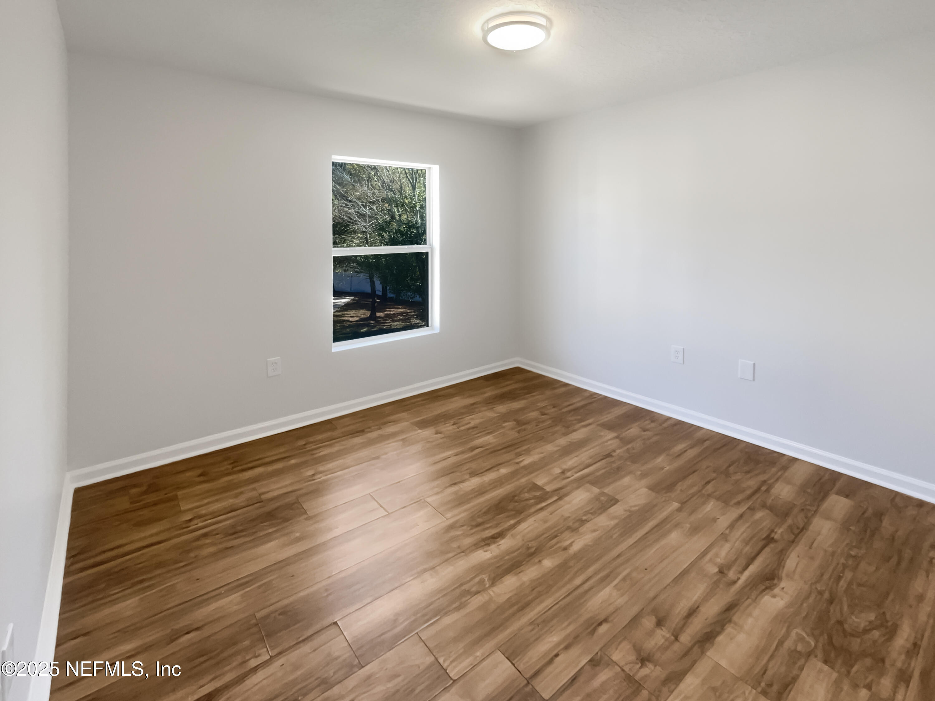 7920 Merrill Road, Unit 1115 Jacksonville, FL 32277 - Photo 18 of 19 an empty room with wooden floor and windows