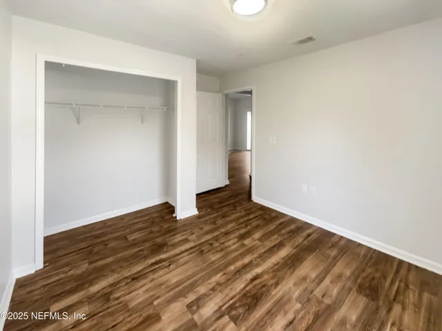 a view of an empty room with wooden floor and closet