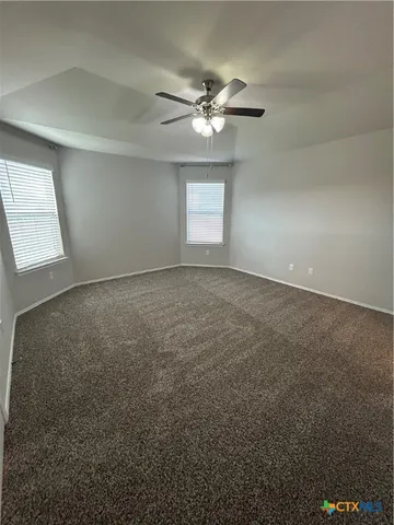 an empty room with windows and fan