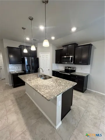 a kitchen with kitchen island granite countertop a sink a counter top space appliances and cabinets