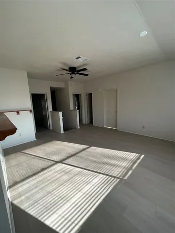 an empty room with windows and ceiling fan