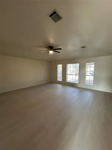 an empty room with a ceiling fan and window