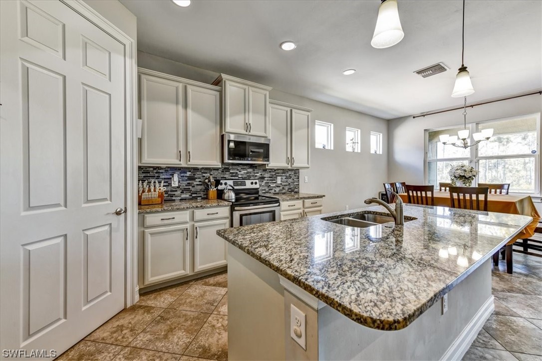 a kitchen with stainless steel appliances granite countertop a sink a stove counter space and cabinets