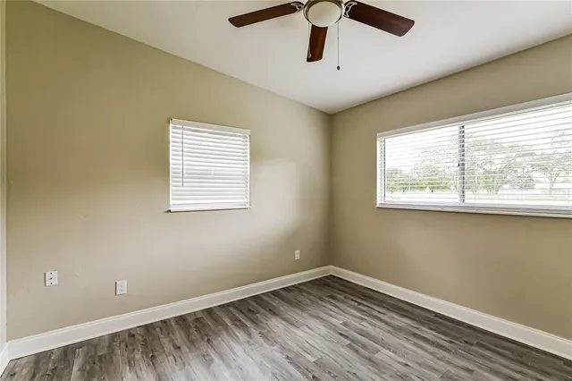 a view of empty room with wooden floor and fan