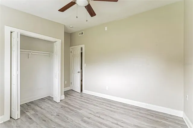 an empty room with wooden floor and ceiling fan
