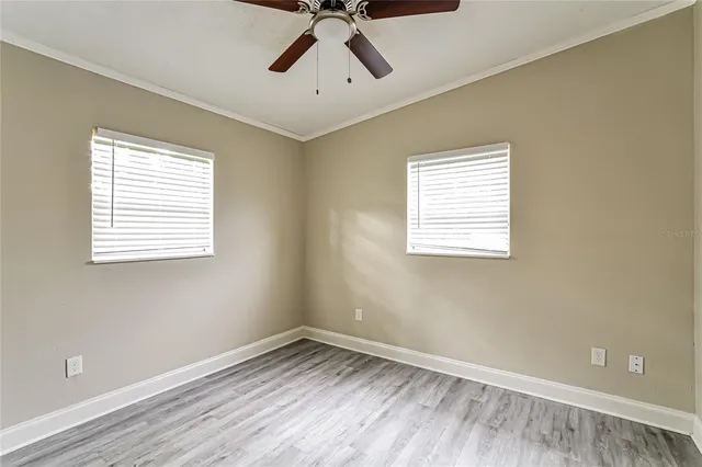 a view of empty room with wooden floor and fan