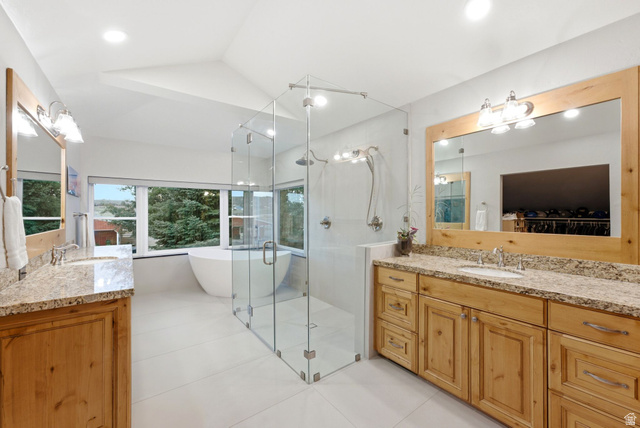 8650 Redden Road Park City, UT 84098 - Photo 19 of 71 Dual wood-finish vanities with stone countertops, a large glass-enclosed shower, a freestanding soaking tub, and multiple windows