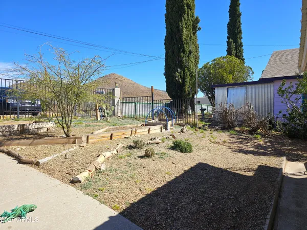 a backyard of a house with table and chairs under an umbrella