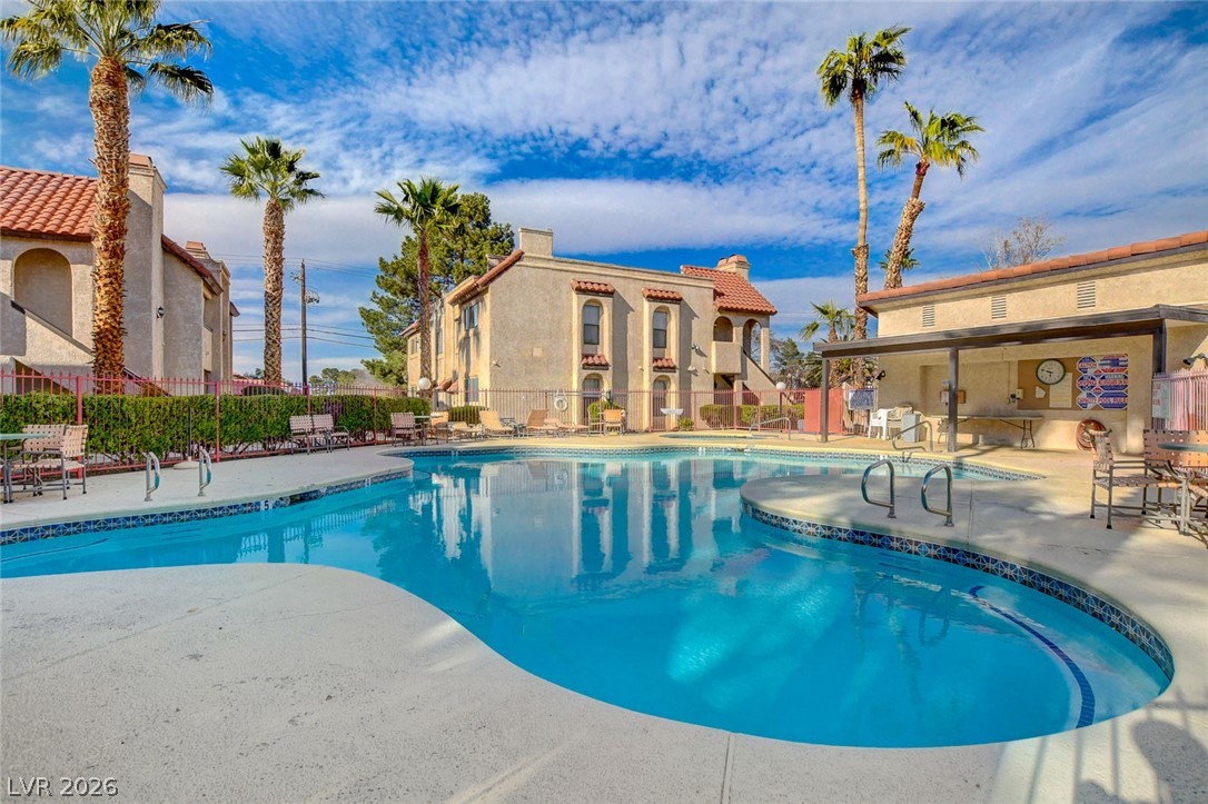 1751 East Reno Avenue, Unit 228 Las Vegas, NV 89119 - Photo 33 of 39 A refreshing pool awaits amidst a backdrop of charming residential buildings and tropical palms.