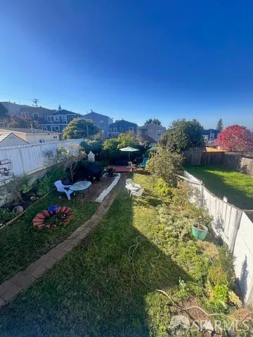 a view of a garden with lawn chairs under an umbrella