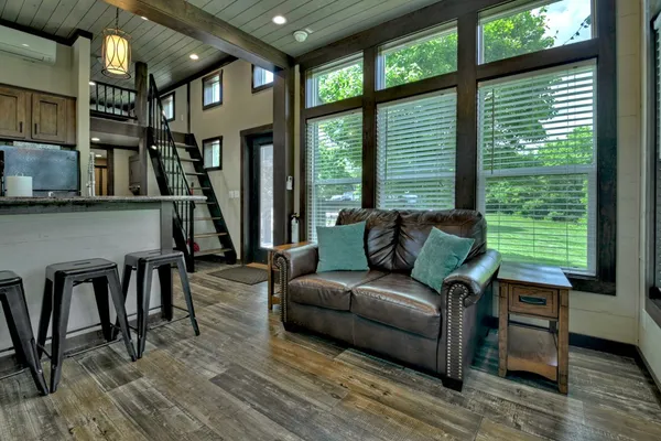 a living room with furniture a large window and wooden floor