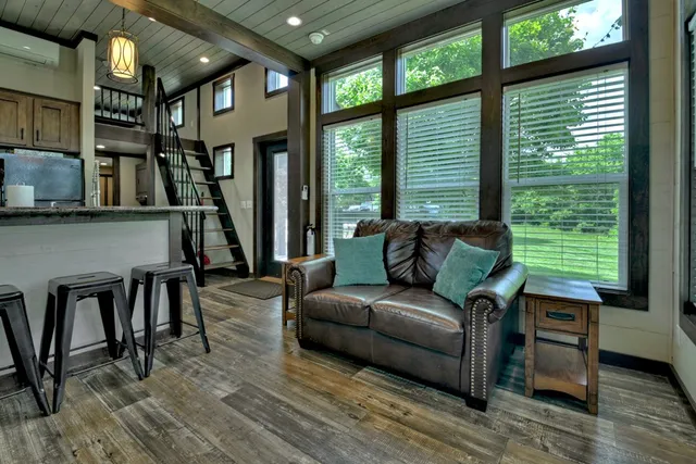 a living room with furniture a large window and wooden floor
