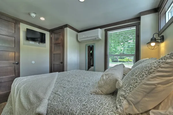 a bedroom with a large bed and a flat tv screen