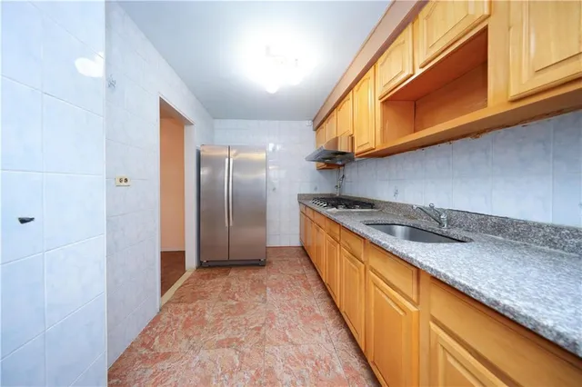 a kitchen with stainless steel appliances granite countertop a sink and a refrigerator