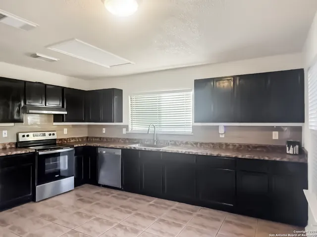 a kitchen with stainless steel appliances granite countertop a sink and a stove