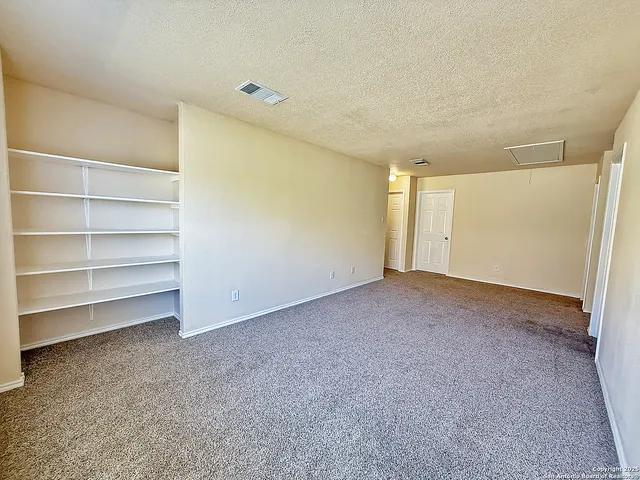 a view of an empty room with a ceiling fan and a window