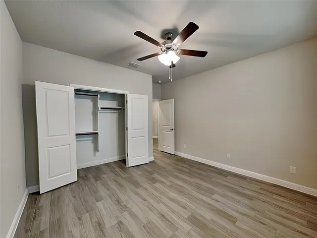a view of an empty room with wooden floor and closet