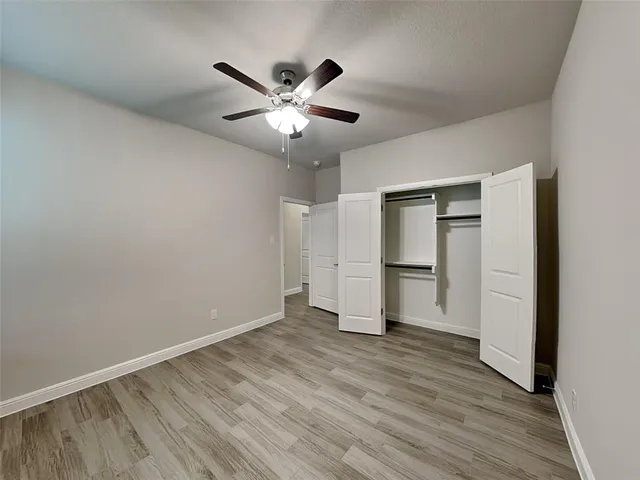 a view of an empty room with wooden floor and window