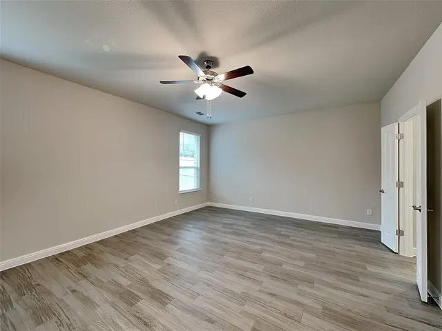 a view of an empty room with window and wooden floor