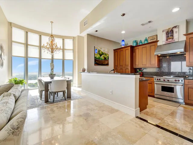 a kitchen with granite countertop a stove a sink a dining table and chairs
