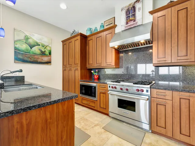 a kitchen with stainless steel appliances granite countertop a stove a sink and a microwave
