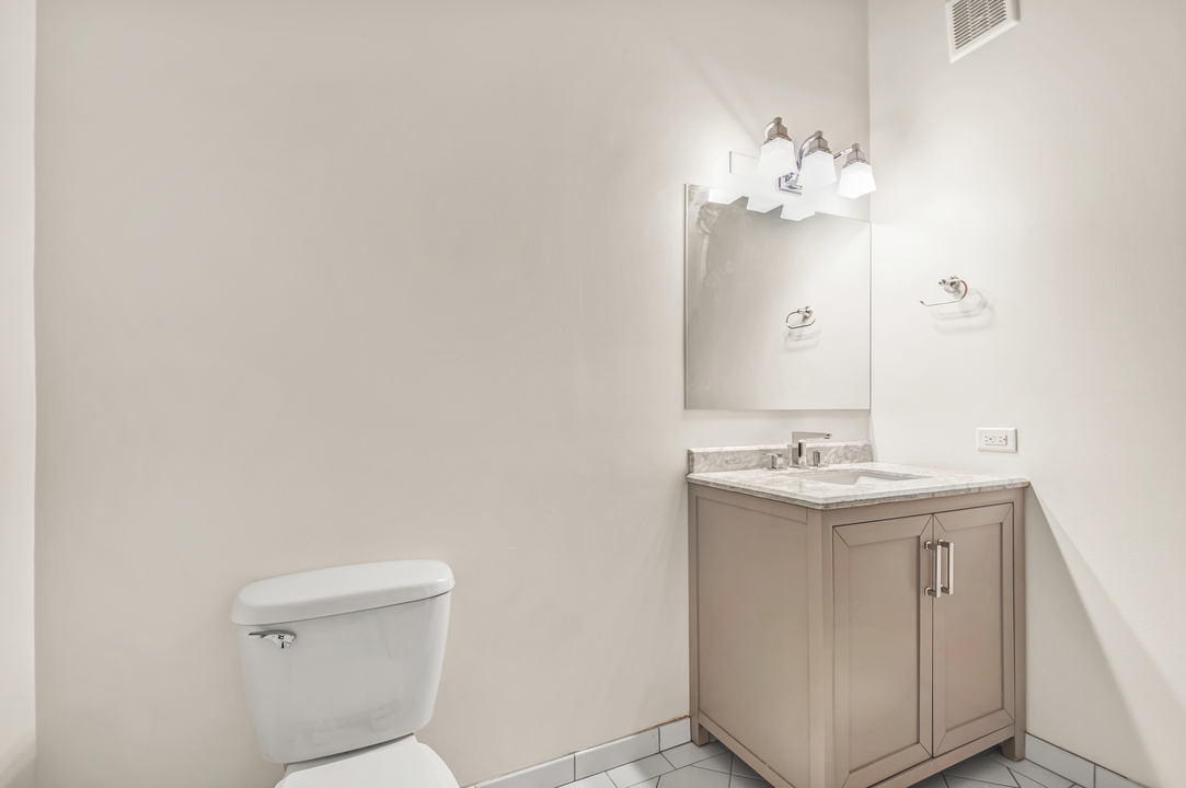 216 North May Street, Unit 103 Chicago, IL 60607 - Photo 18 of 21 a bathroom with a sink a toilet and mirror