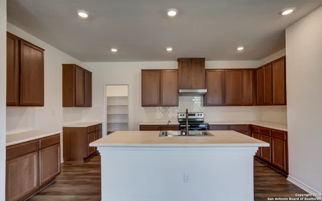 a kitchen with kitchen island granite countertop a sink and a stove top oven with wooden floors