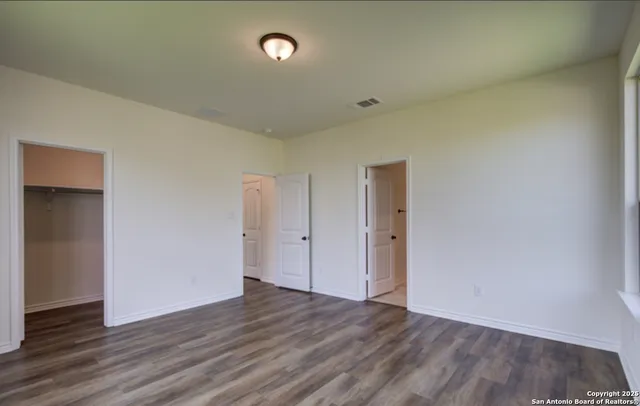 a view of an empty room with wooden floor and closet