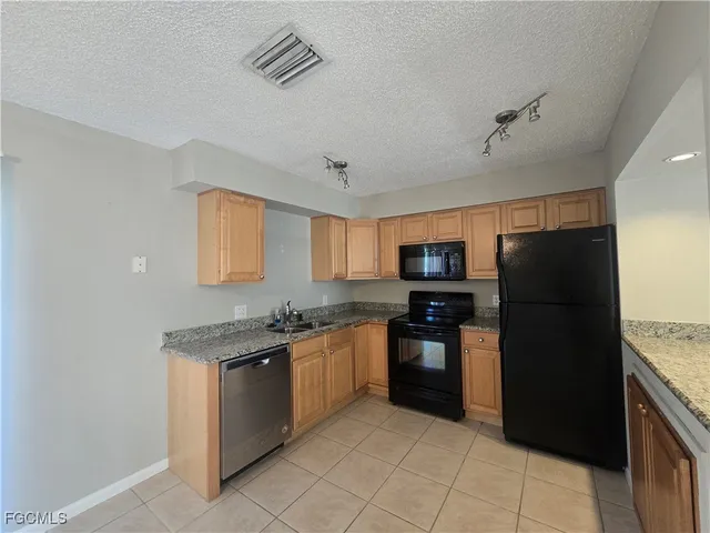 a large kitchen with stainless steel appliances granite countertop a refrigerator and a stove