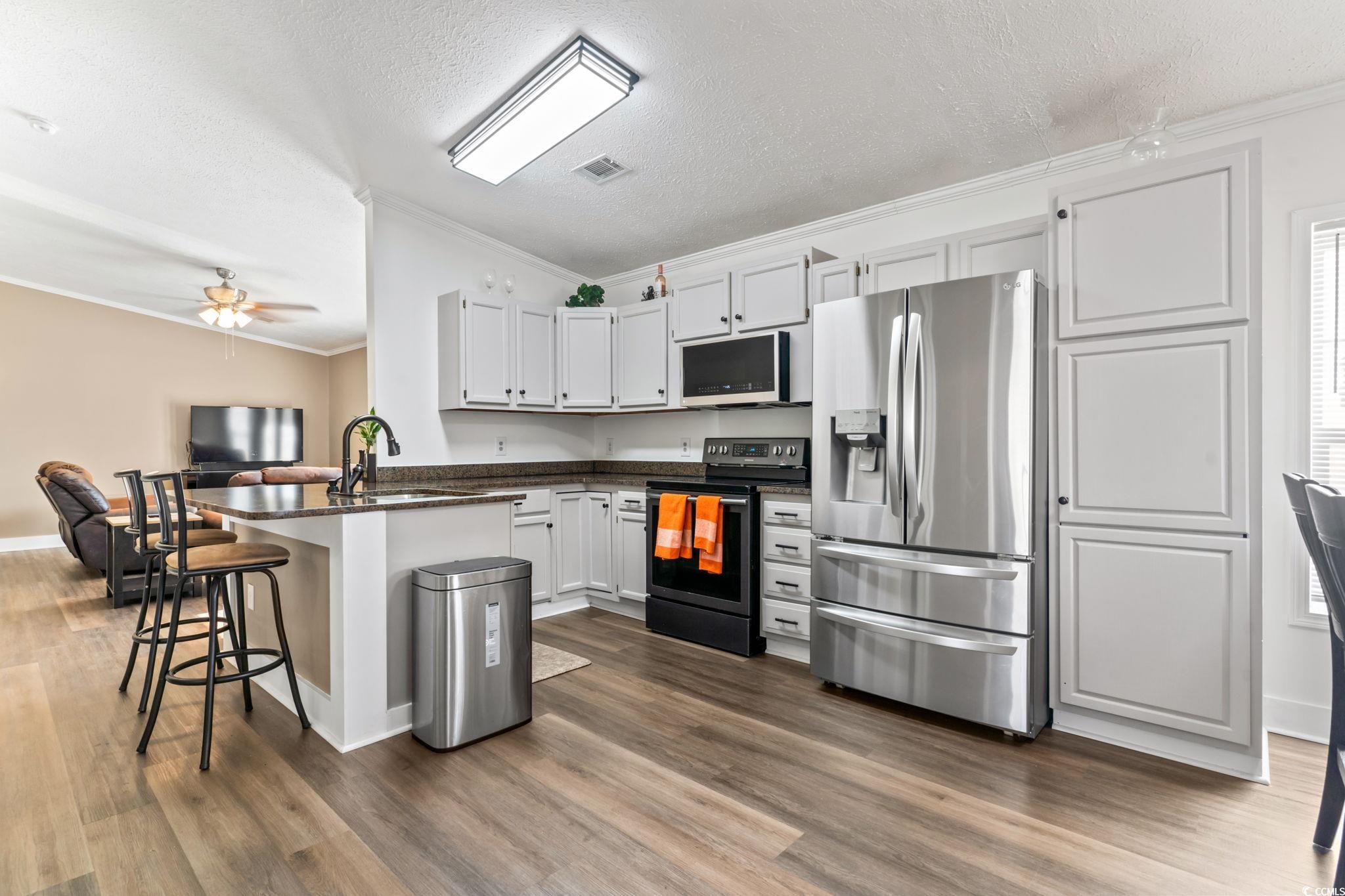 2977 Silverleaf Circle Loris, SC 29569 - Photo 10 of 36 Kitchen featuring stainless steel fridge, electric stove, a breakfast bar area, crown molding, and a textured ceiling